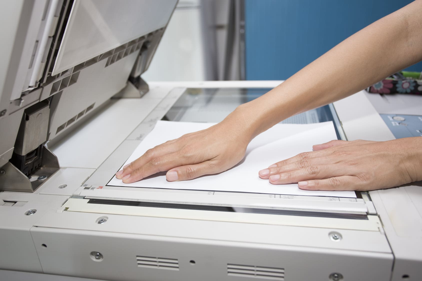 woman hands putting a sheet of paper into a copying device